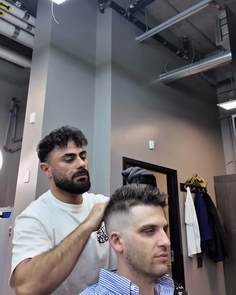 A Barberhood York U barber finishing an adult client's haircut